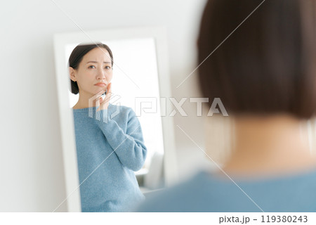 鏡を見て困った表情をする40代女性 119380243