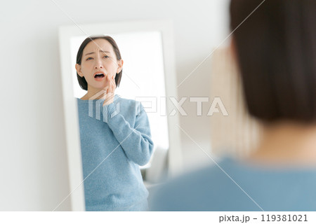 鏡で歯のチェックをする40代女性 119381021