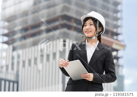 スーツにヘルメット被ってタブレットをもつ若い女性　施工管理者　現場監督　土木女子（ドボジョ） 119381575