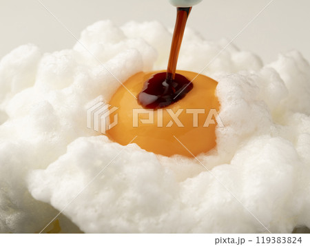 ご飯に乗せた泡立てた卵白の上の卵黄に醤油をかける 119383824