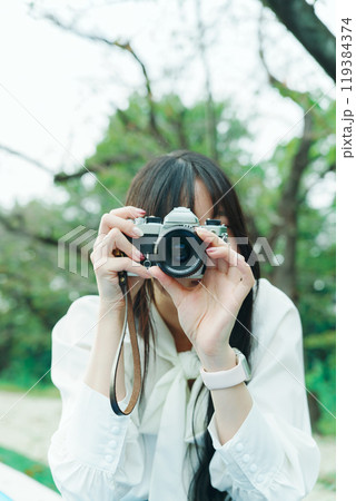 フィルムカメラのファインダーを覗く女性 フィルムカメラのファインダーを覗く女性 119384374