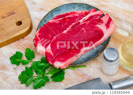 Slices of raw veal tenderloin on plate with greens 119385049