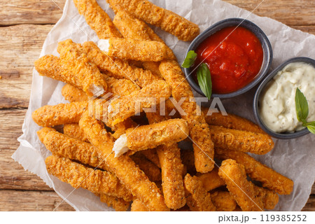 Dip fried Breaded chicken breast strips served with ketchup and mayo close-up on parchment. Horizontal top view Dip fried Breaded chicken breast strips served with ketchup and mayo close-up on parchment. Horizontal top view 119385252