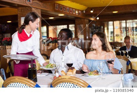 Ordinary female waiter carrying order for visitors in restaurant Ordinary female waiter carrying order for visitors in restaurant 119385340