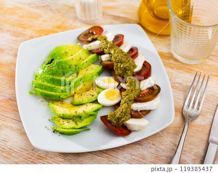 Slices of mozzarella and tomatoes - Italian salad caprese with addition boiled eggs and avocado Slices of mozzarella and tomatoes - Italian salad caprese with addition boiled eggs and avocado 119385437