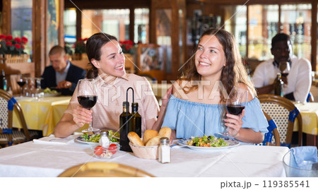 Two girls are discussing something fun at a table in restaurant 119385541