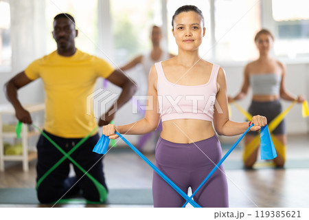 Asian woman doing resistance band exercises at group pilates session 119385621