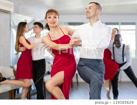 Cheerful woman in red dancing lindy hop with man during group class Cheerful woman in red dancing lindy hop with man during group class 119385629