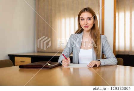 Positive young businesswoman writes notes while in a conference room Positive young businesswoman writes notes while in a conference room 119385864