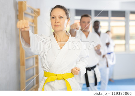 Women and men in kimono in fight stance during group karate training 119385866