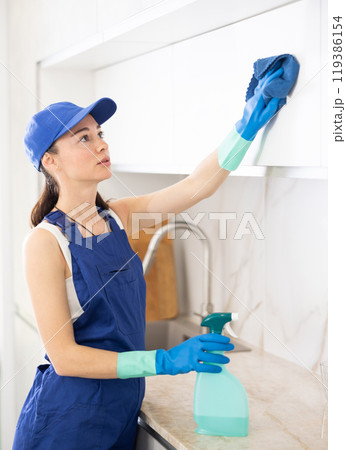 young positive girl is cleaning kitchen young positive girl is cleaning kitchen 119386154
