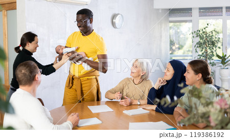 Positive african american man holding baby in arms during work meeting Positive african american man holding baby in arms during work meeting 119386192