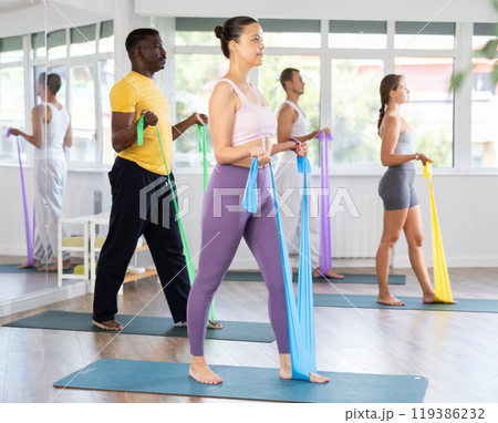 Asian woman doing resistance band exercises at group pilates session 119386232