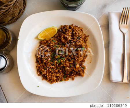 Plate is filled with paella made according to Spanish recipe from rice cereals, seafood, and chicken 119386349