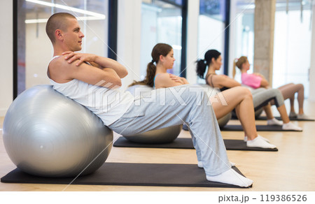 Focused man doing workout with pilates ball 119386526