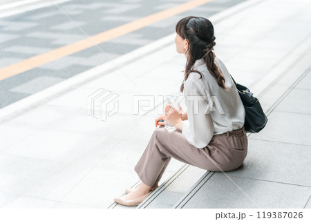 ペットボトルを持って座るビジネスウーマン(水分補給・休憩・ミネラルウォーター) ペットボトルを持って座るビジネスウーマン(水分補給・休憩・ミネラルウォーター) 119387026
