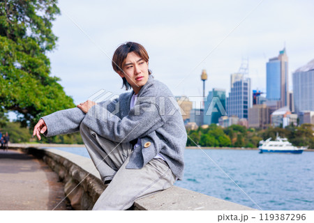オーストラリアの海沿いに座る日本人男性 119387296