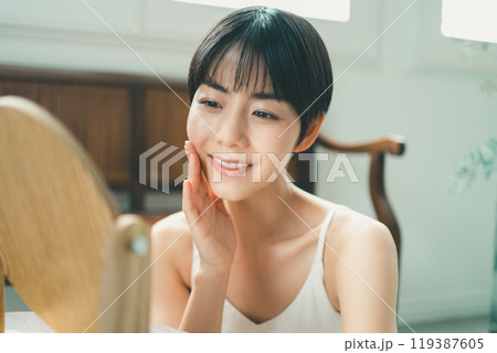 木製の卓上ミラーを見てスキンケアをする女性 木製の卓上ミラーを見てスキンケアをする女性 119387605