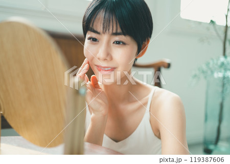 木製の卓上ミラーでスキンケアをする女性 木製の卓上ミラーでスキンケアをする女性 119387606
