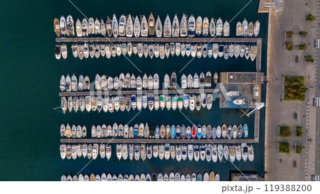 Aerial view of a marina in Marseille, France, with boats and yachts docked in neat rows along the waterfront. The deep blue water contrasts beautifully with the vessels. Aerial view of a marina in Marseille, France, with boats and yachts docked in neat rows along the waterfront. The deep blue water contrasts beautifully with the vessels. 119388200