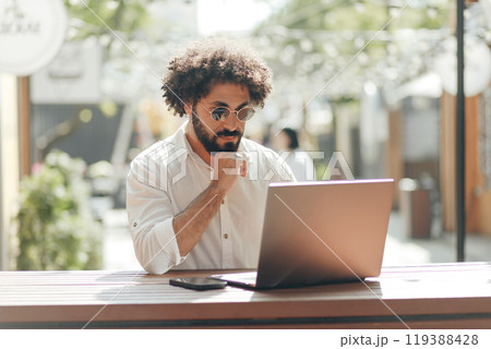 Business portrait, Arabian businessman sitting with laptop computer in outdoors cafe. Freelancer working outdoors 119388428