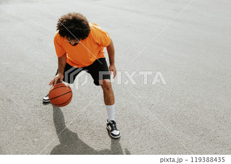 Full length portrait of a young african man playing basketball on the court outdoors 119388435