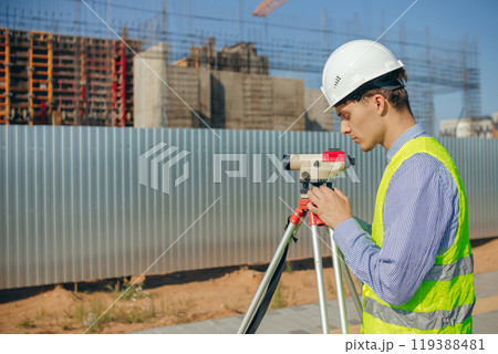 Surveyor engineer adjust optical level on construction site 119388481