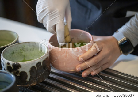 Woman whisking matcha powder while making matcha green tea with traditional accessories for tea ceremony Woman whisking matcha powder while making matcha green tea with traditional accessories for tea ceremony 119389037