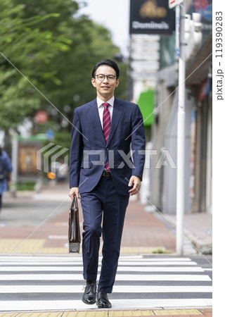 ビジネスバッグを持って街を歩くミドルのビジネスマン　 119390283