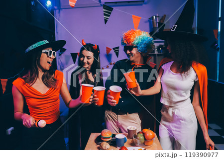 Joyful office Halloween party with coworkers in costumes, celebrating with drinks and laughter, fostering teamwork and festive spirit 119390977