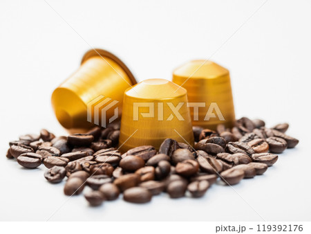 Coffee capsules with fresh raw aroma beans on white background. Coffee capsules with fresh raw aroma beans on white background. 119392176