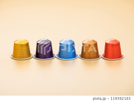 Various aluminium capsules of natural organic coffee suitable for coffee machine on beige background. 119392183