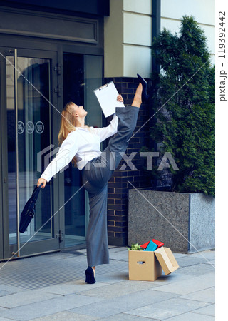 Joy of freedom. Happy young woman in formal wear dancing outside the office, expressing positive emotions after quitting job Joy of freedom. Happy young woman in formal wear dancing outside the office, expressing positive emotions after quitting job 119392442