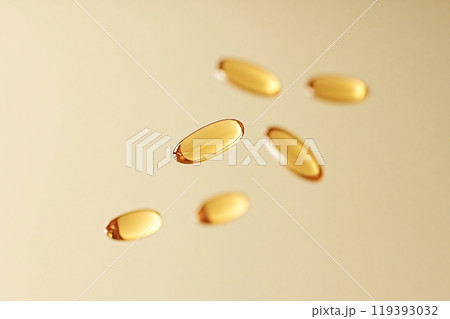 Golden vitamin pills floating on a soft gold background 119393032