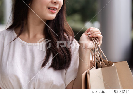Stylish Woman Enjoying a Shopping Spree at the Mall with Eco-Friendly Paper Bags in Hand 119393214