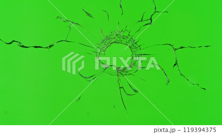 Close-up of gunshot through the glass, shattering against the green background Close-up of gunshot through the glass, shattering against the green background 119394375