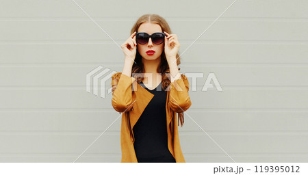 Fashion portrait elegant woman wearing a sunglasses jacket over grey background Fashion portrait elegant woman wearing a sunglasses jacket over grey background 119395012