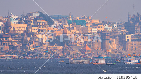 Varanasi, Uttar Pradesh, India. Many Boats are moored to the Ganga riverbank. Tourists boarding for an overnight boats ride on the Ganges River. Cityscape of Varanasi is visible - embankment in the Varanasi, Uttar Pradesh, India. Many Boats are moored to the Ganga riverbank. Tourists boarding for an overnight boats ride on the Ganges River. Cityscape of Varanasi is visible - embankment in the 119395419