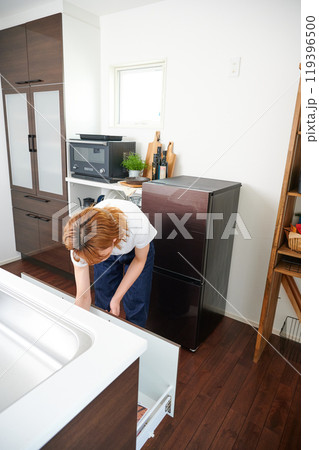 食器棚をあける女性　主婦　家事　料理　片付け 119396500