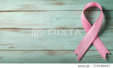 A pink breast cancer awareness ribbon is placed on a rustic teal wooden background, symbolizing hope and support. A pink breast cancer awareness ribbon is placed on a rustic teal wooden background, symbolizing hope and support. 119396607