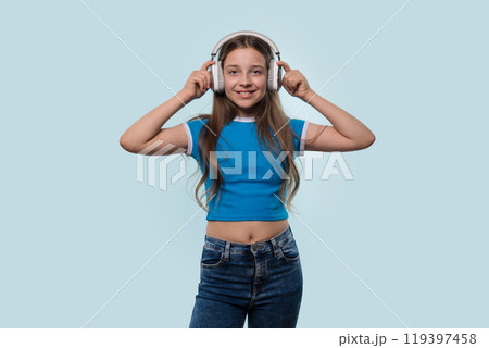 Girl in blue t-shirt smiling while wearing headphones. Girl in blue t-shirt smiling while wearing headphones. 119397458