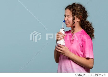 Young girl grimacing while using an oral irrigator Young girl grimacing while using an oral irrigator 119397473