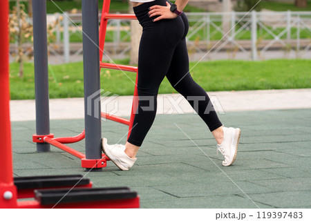Woman stretching leg against fitness equipment 119397483