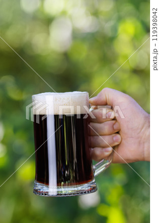closeup male hand with mug of dark beer closeup male hand with mug of dark beer 119398042