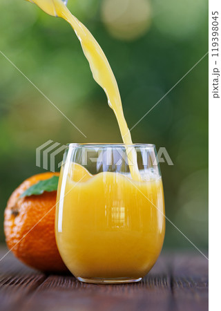 orange juice pouring into glass on table outdoors orange juice pouring into glass on table outdoors 119398045