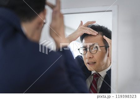 鏡を見ながら髪の生え際を気にする30代後半のビジネスマン 119398323