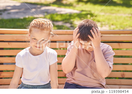 Playful kids on bench smiling girl and upset boy in sunny park scene capturing Playful kids on bench smiling girl and upset boy in sunny park scene capturing 119398454