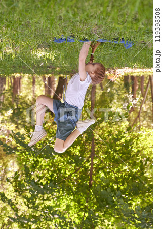 Playful child enjoying outdoor zip line adventure in lush green park setting 119398508