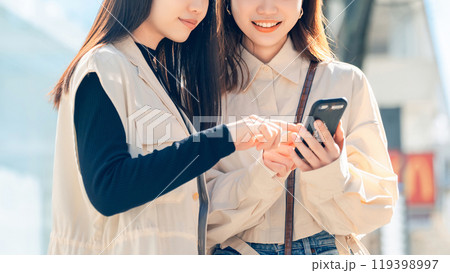 街中でスマホを見る友達同士の若い女性 街中でスマホを見る友達同士の若い女性 119398997