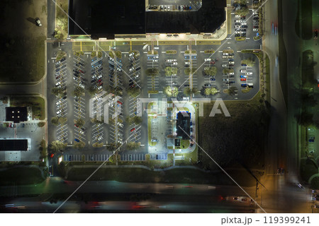 View from above of many parked cars on illuminaded parking lot with lines and markings for parking places and directions. Place for vehicles in front of a shopping mall center View from above of many parked cars on illuminaded parking lot with lines and markings for parking places and directions. Place for vehicles in front of a shopping mall center 119399241